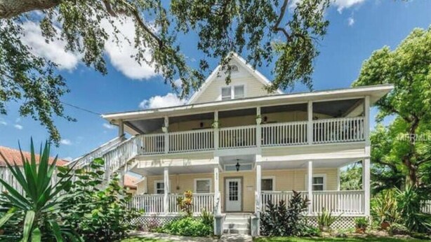 A two-story house with a front porch, a staircase leading to the entrance, and a well-maintained garden. - 2 Bedroom Apt Overlooking Dunedin Town Square (Dunedin)