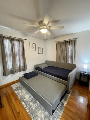 Une chambre à coucher avec un lit, un ventilateur de plafond et une petite table de chevet.