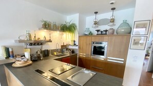 A modern kitchen with a central island, stainless steel appliances, and wooden cabinetry.