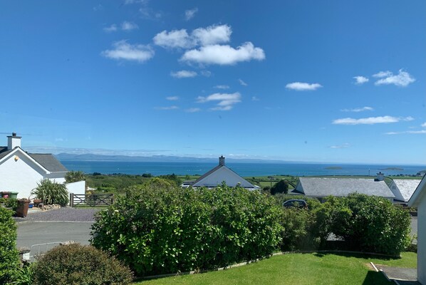 A residential area with houses, a clear sky, and a view of the sea. - Watlands (Pwllheli)