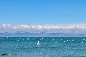 A marina with various boats and sailboats, a clear sky, and distant mountains. - Watlands (Pwllheli)
