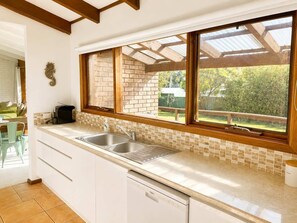 Una cucina con un'ampia finestra, un lavello e una lavastoviglie.