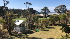 A fenced yard with a small white shed, a green ball, and a grassy area. - Tee to Sea - 3BR home with golf & ocean views (Mollymook)