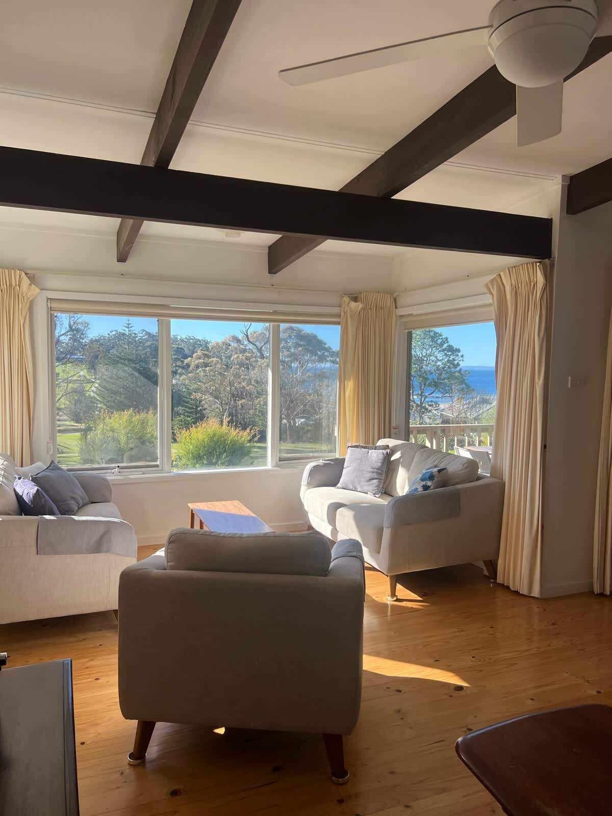 A spacious living room with a large window, a ceiling fan, and a view of the outdoors.