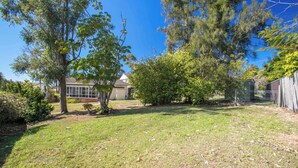 A residential backyard with a house, trees, and a fenced area. - So Close to the Beach (Mollymook)