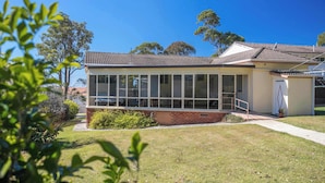 A modern house with a large glass windowed front, a brick base, and a tiled roof. - So Close to the Beach (Mollymook)
