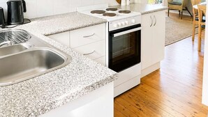 Una cocina moderna con armarios blancos, encimera de granito, estufa y fregadero.