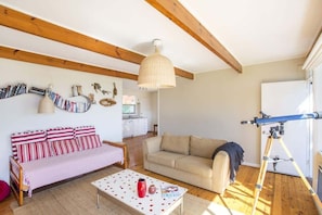 A cozy living room with a sofa, a coffee table, and a telescope. - Stunning Views at Dolphin Point (Dolphin Point)