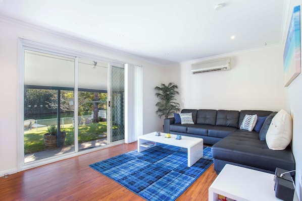 A modern living room with a black sofa, a white coffee table, and a blue rug.