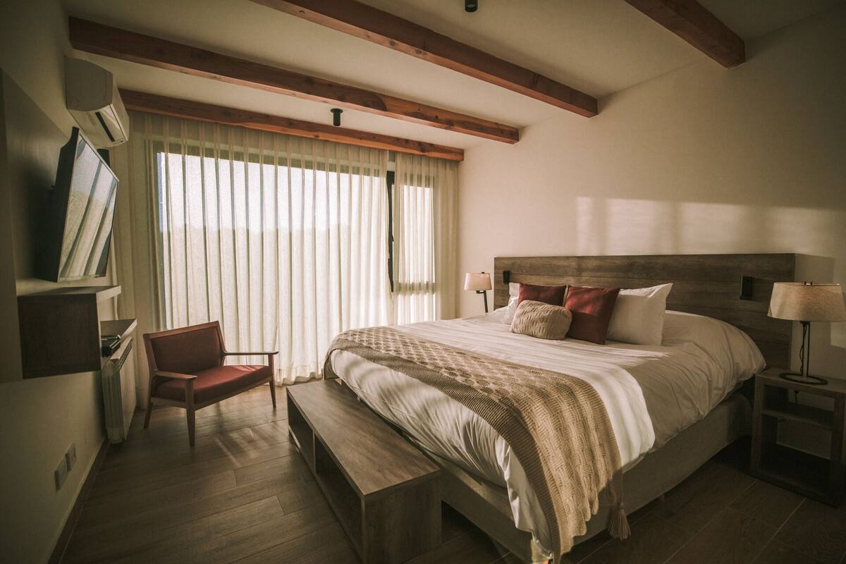 A bedroom with a large bed, a desk, and a chair.