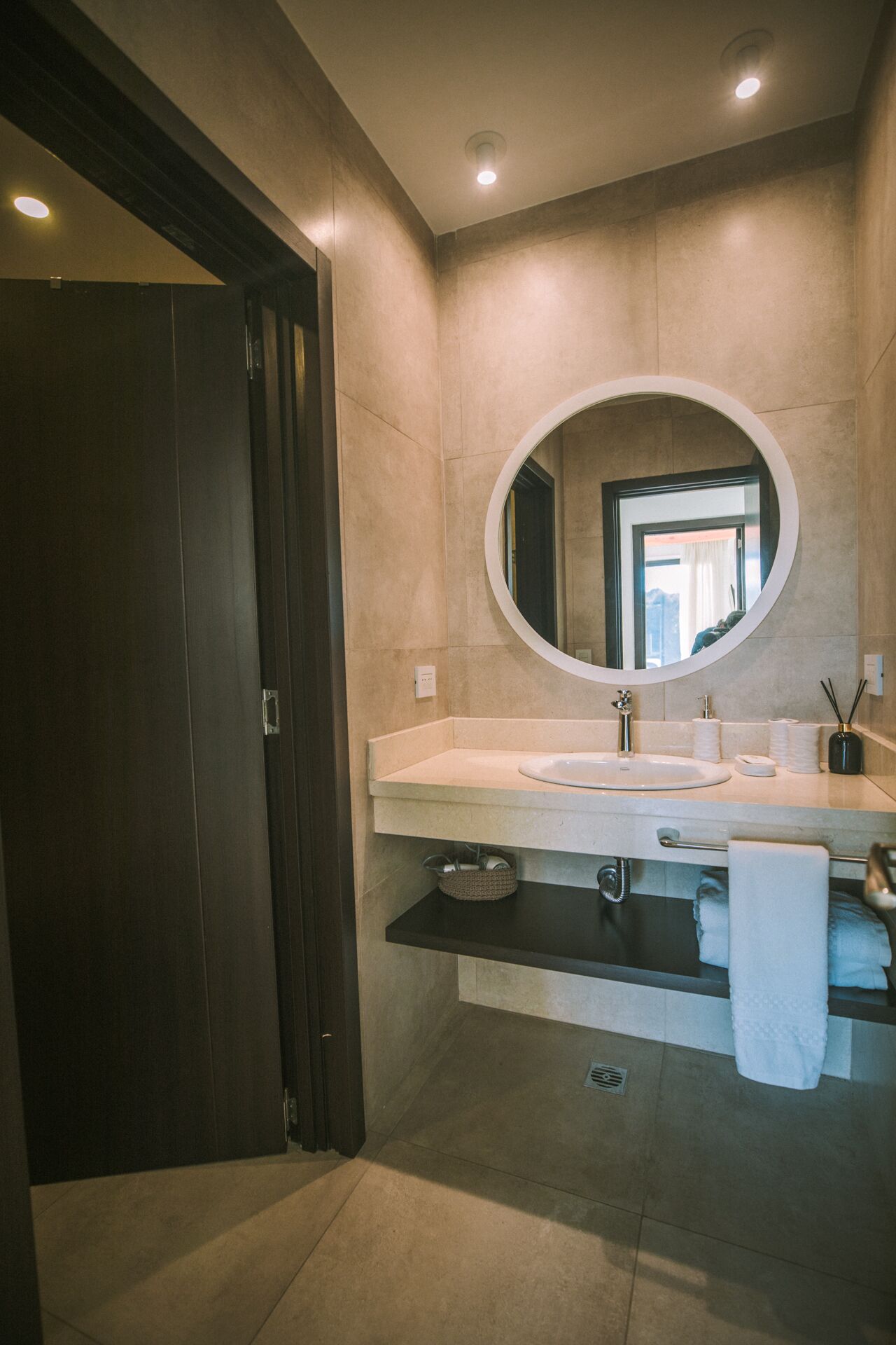 A modern bathroom with a large mirror, a sink, and a towel rack.