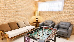 Une pièce avec un baby-foot, un canapé et deux fauteuils.