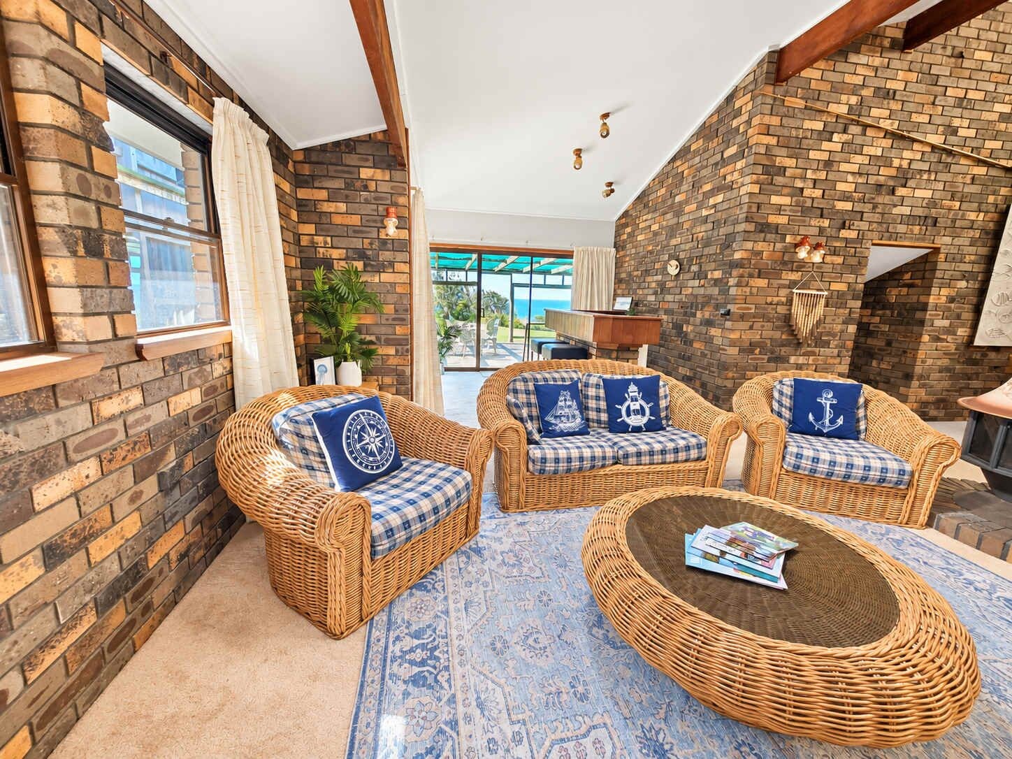A cozy room with wicker furniture, a patterned rug, and a brick wall.