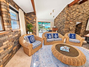 A cozy room with wicker furniture, a patterned rug, and a brick wall.