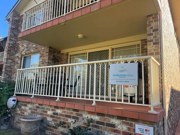 A two-story building with a balcony, a sign for 'Mollymookmilton Holidays', and a water tank. - Perfect Location Near Collers Beach (Mollymook)