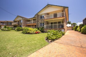 A two-story hotel with a brick facade, balconies, and a well-maintained lawn.