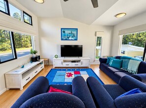 A modern living room with a flat-screen TV, a blue rug, and a sofa.