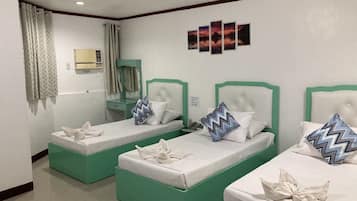 Habitación de hotel con dos camas individuales, cada una con estructura verde y ropa de cama blanca. Hay una mesita de noche pequeña con una lámpara, un espejo y una ventana con cortinas.