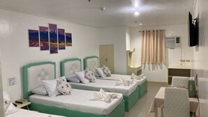 A hotel room with three beds, a small table, and a TV. - Demiren Hotel and Restaurant (Cagayan de Oro)