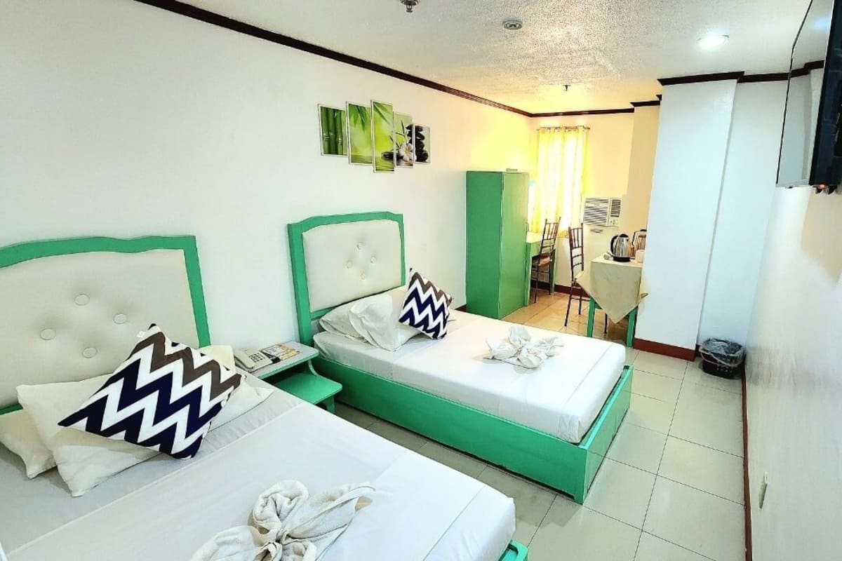 A hotel room with two beds, a desk, and a chair.