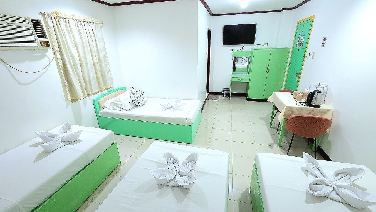 Una habitación de hotel con dos camas, un escritorio, una silla, un televisor y un armario verde.