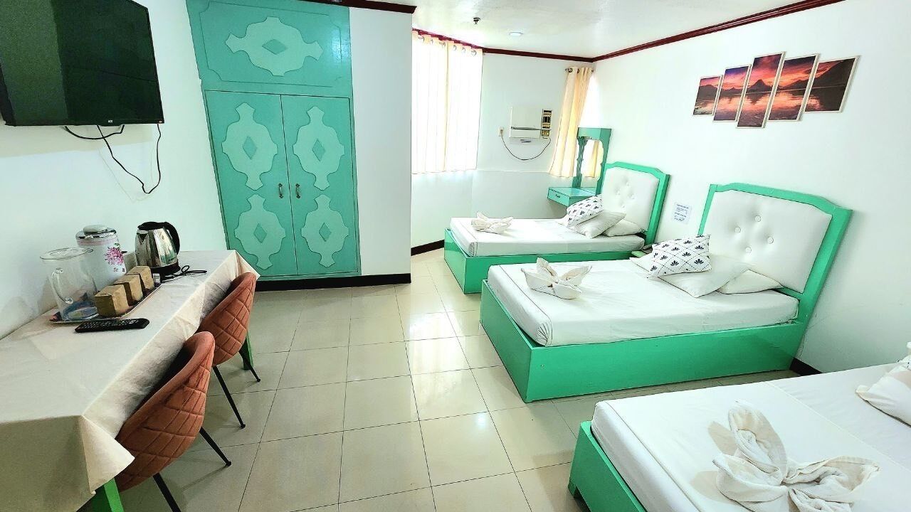 Habitación de hotel con dos camas, un escritorio, sillas, un televisor, armario y baño.