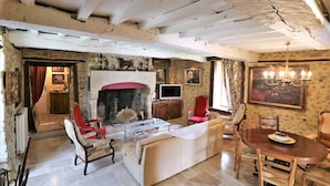 A rustic living room with a fireplace, stone walls, and a chandelier.