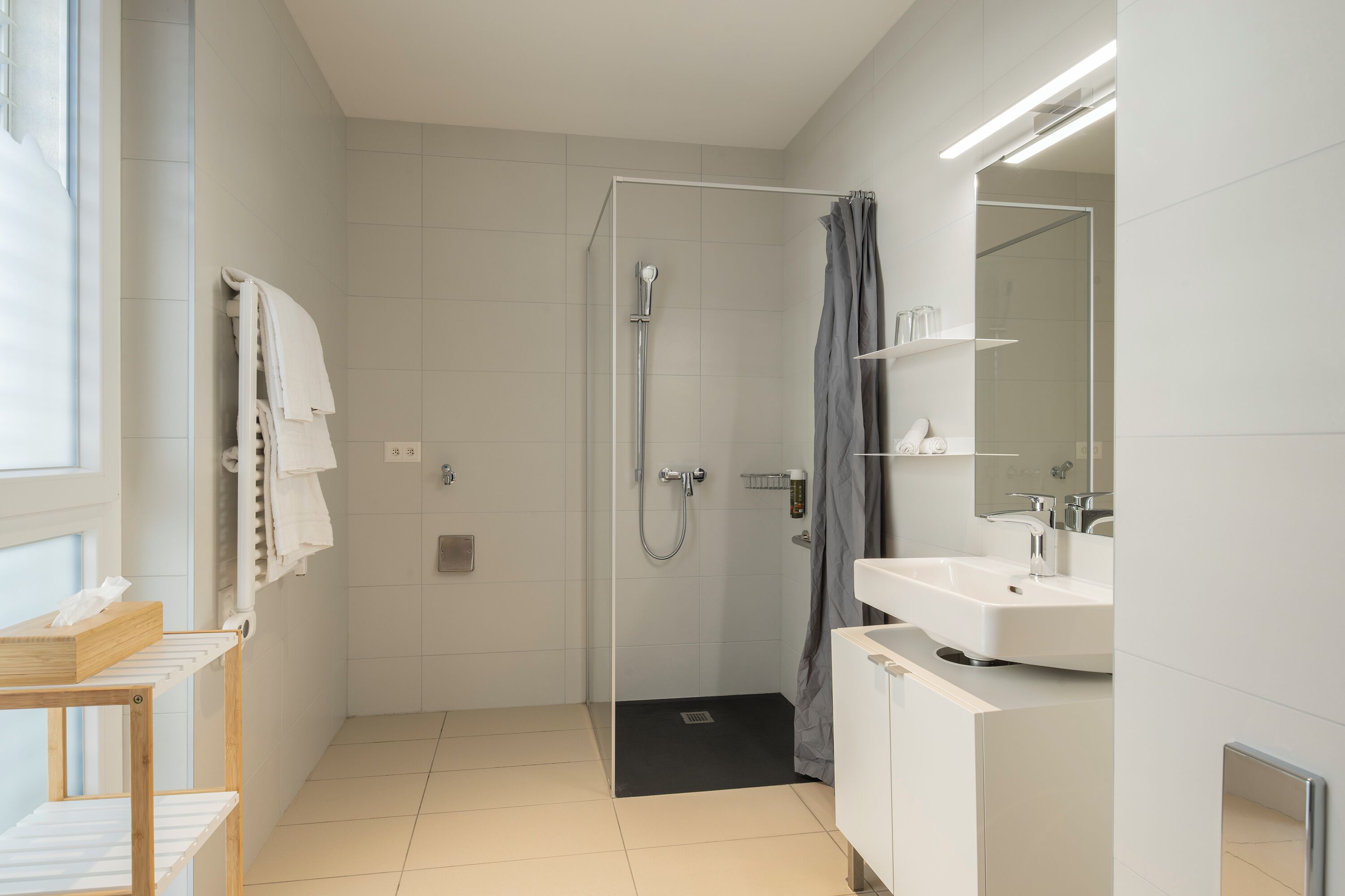 A modern bathroom with a shower, a sink, and a mirror.