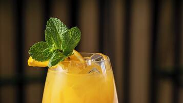 Un verre à cocktail, agrémenté d’un fruit, posé sur une surface réfléchissante.