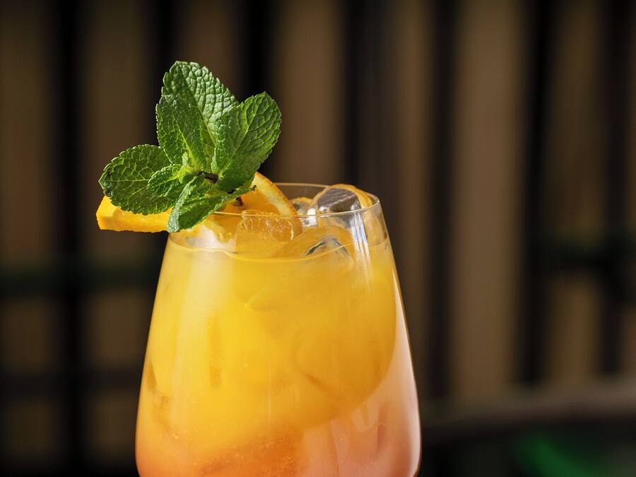A cocktail glass with a fruit garnish on a reflective surface.