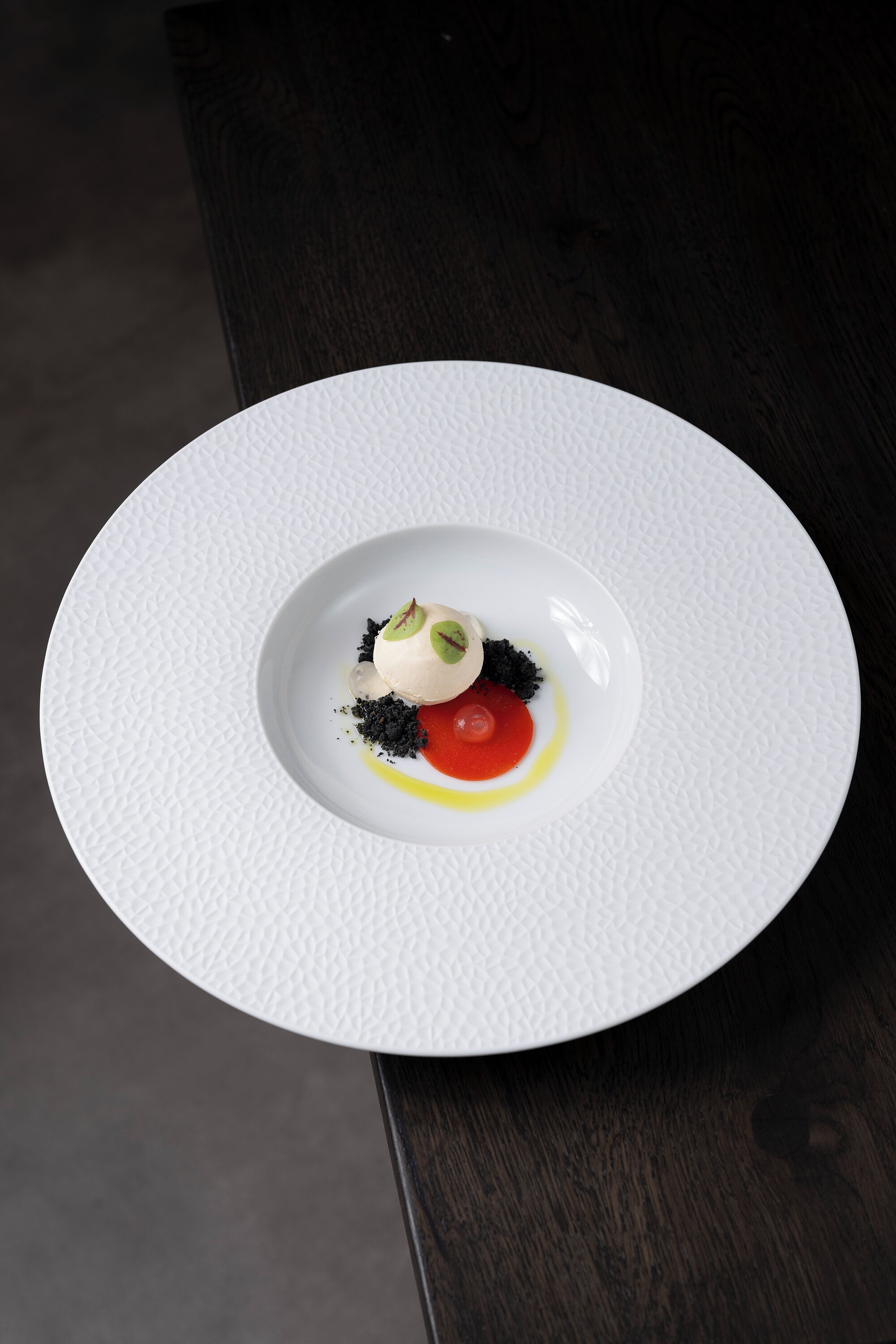 Ein weißer Teller mit Dessert auf einem dunklen Holztisch.