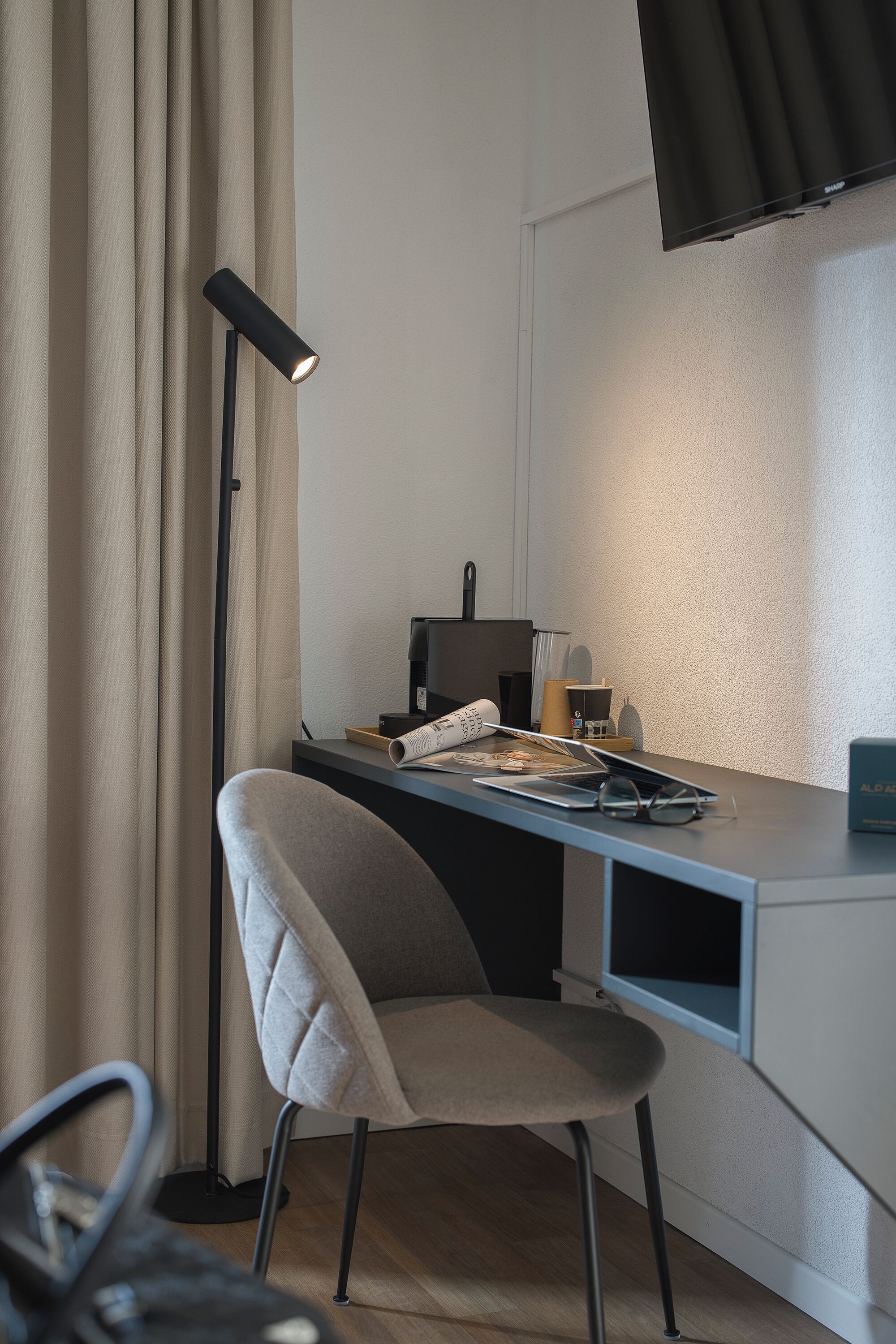 Un espace de bureau moderne comprenant un bureau, une chaise, une lampe et un téléviseur à écran plat.