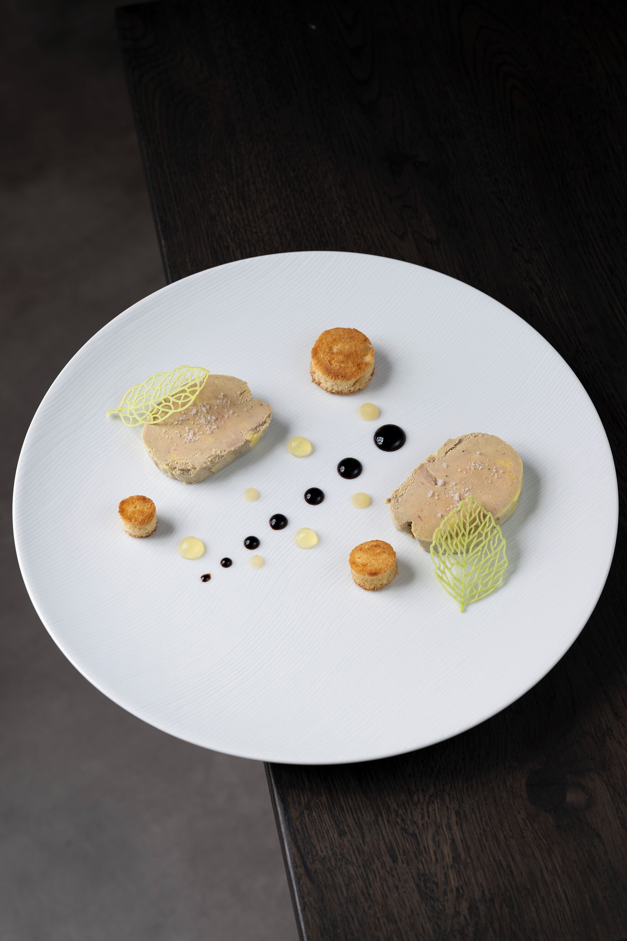 A white plate with a dessert consisting of two round items, small round items, and decorative elements.
