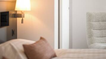 Una habitación de hotel con una cama, un reloj en la pared, una lámpara y una silla.