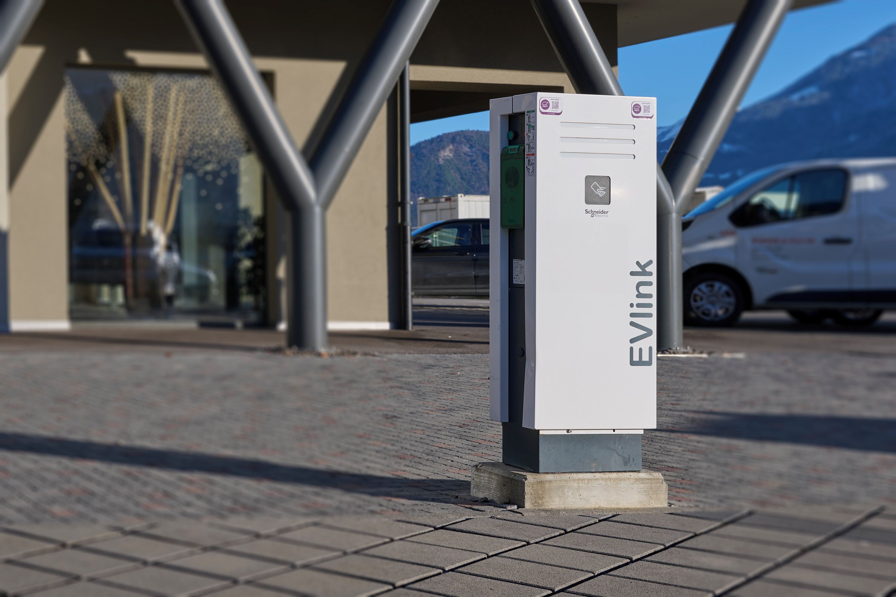 An EVlink charging station in an urban setting with a modern building in the background.