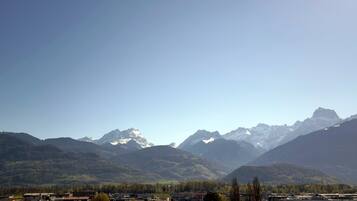 A mountainous landscape with snow-capped peaks and a valley with buildings.