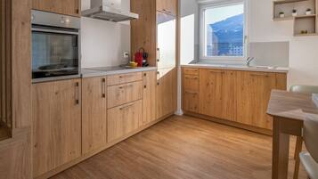 Una cocina con armarios de madera, horno empotrado, ventana con vistas y un lavabo.