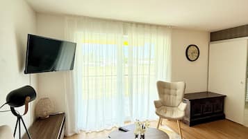 Suíte júnior, 1 cama King, acessível, sacada | Área de estar | TV de tela plana 42 polegadas com canais a cabo, TV, Netflix