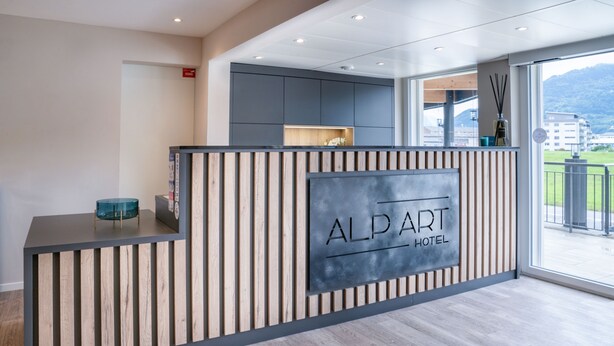 A reception desk with a modern design, featuring a sign that reads "ALP ART HOTEL." - Alparthotel  (Collombey-Muraz)