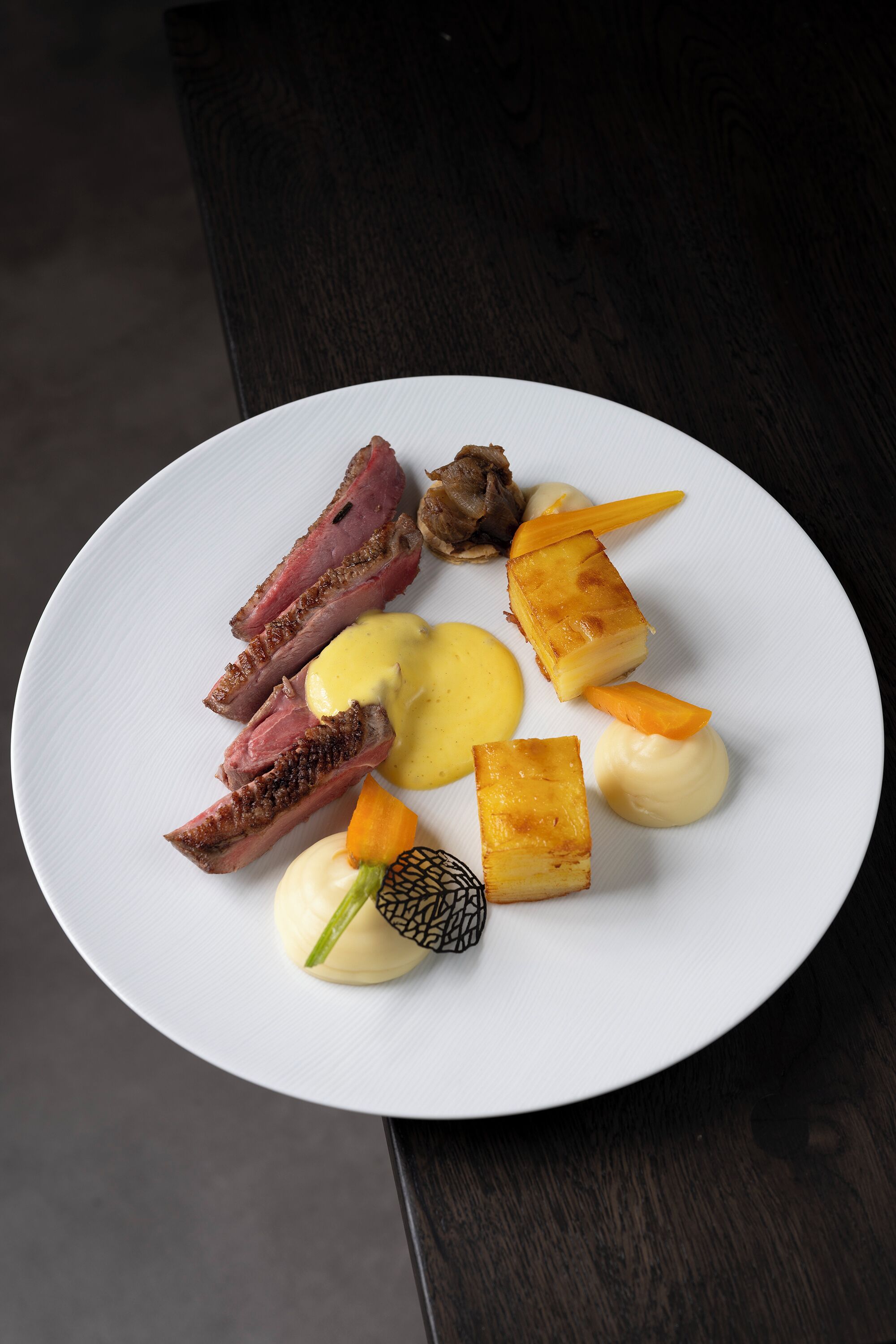 Une assiette blanche contenant divers aliments, notamment de la viande, du fromage et des légumes.