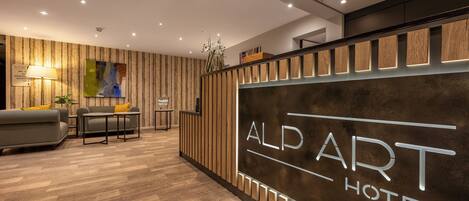 A reception area with a wooden panel wall, a sofa, a table, and a lamp.