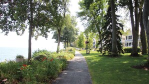 Un sentier pavé, bordé d’arbres et d’arbustes, qui mène à un plan d’eau.