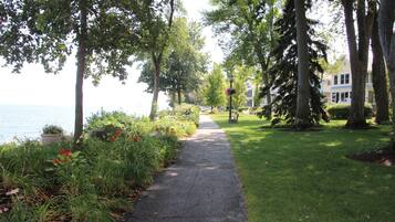Un sentier pavé, bordé d’arbres et d’arbustes, qui mène à un plan d’eau.