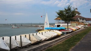 Une rangée de bateaux était alignée le long d’un quai, d’une jetée et d’un bâtiment dont le toit était rouge.