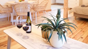 A modern living room with a wooden floor, a dining area with wicker chairs, a flat-screen TV mounted on the wall, and a potted plant on a marble table. - Dream Apart Apartamenty 51 (Ustron)