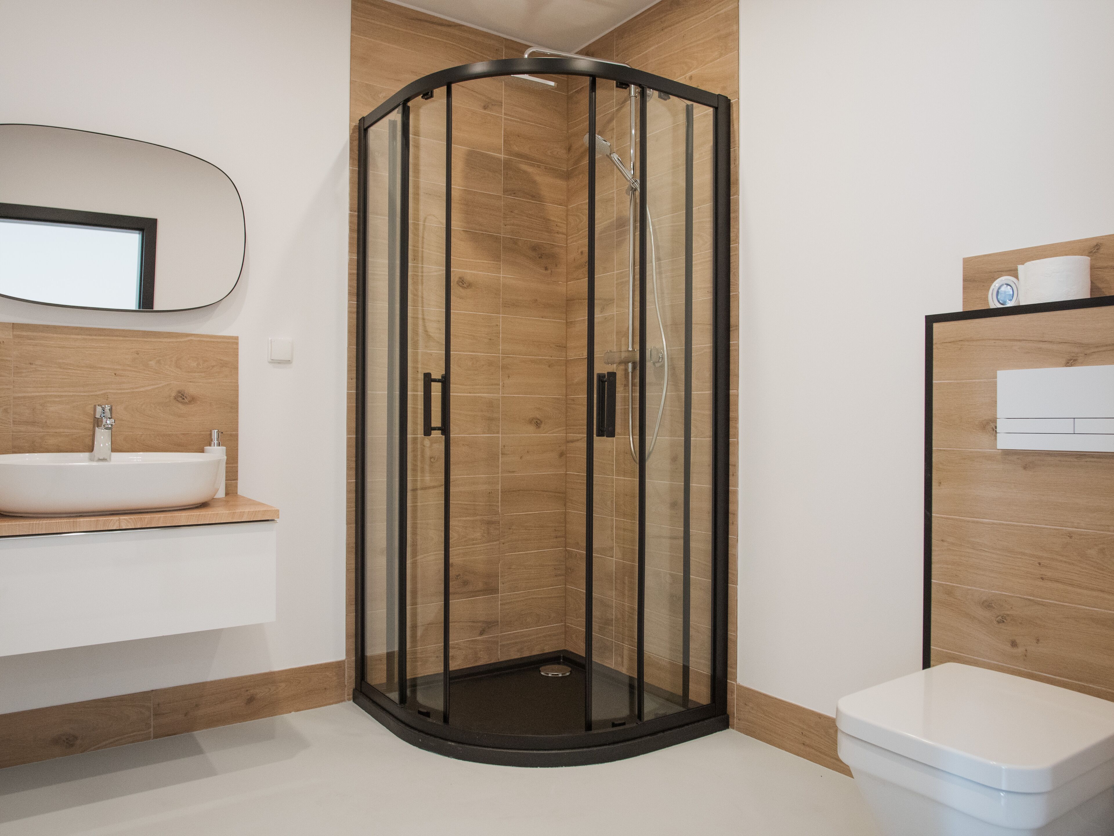 A modern bathroom with a glass-enclosed shower, a sink, and a toilet.