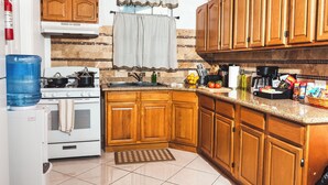 Cozinha com armários de madeira, fogão, pia e diversos utensílios.