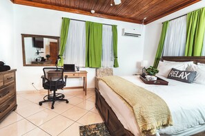 Un dormitorio con cama, escritorio, silla, cómoda y espejo.