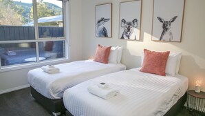 Habitación de hotel con dos camas, una ventana que ofrece vistas a un edificio y árboles, y tres cuadros con imágenes de animales en la pared.