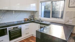 Una cocina moderna con armarios blancos, encimera negra y una ventana sobre el fregadero.